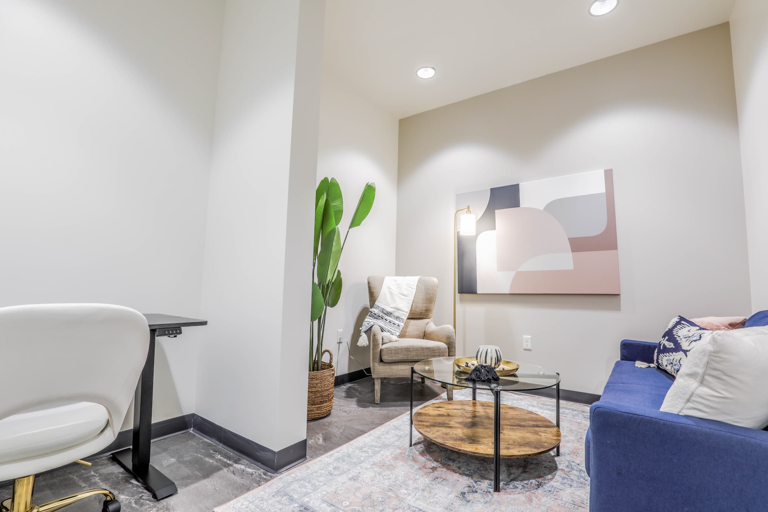Suite with a navy sofa, armchair, round coffee table and a standing desk
